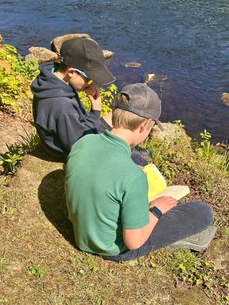 Two children sat sketching by a river